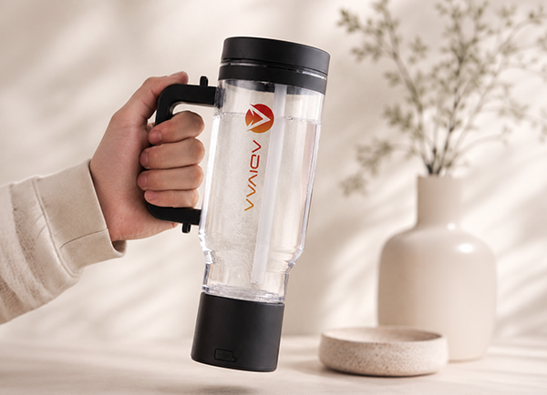 Hand holding a clear blender cup with black lid and base, featuring the Vivaiv brand logo, against a blurred indoor background.