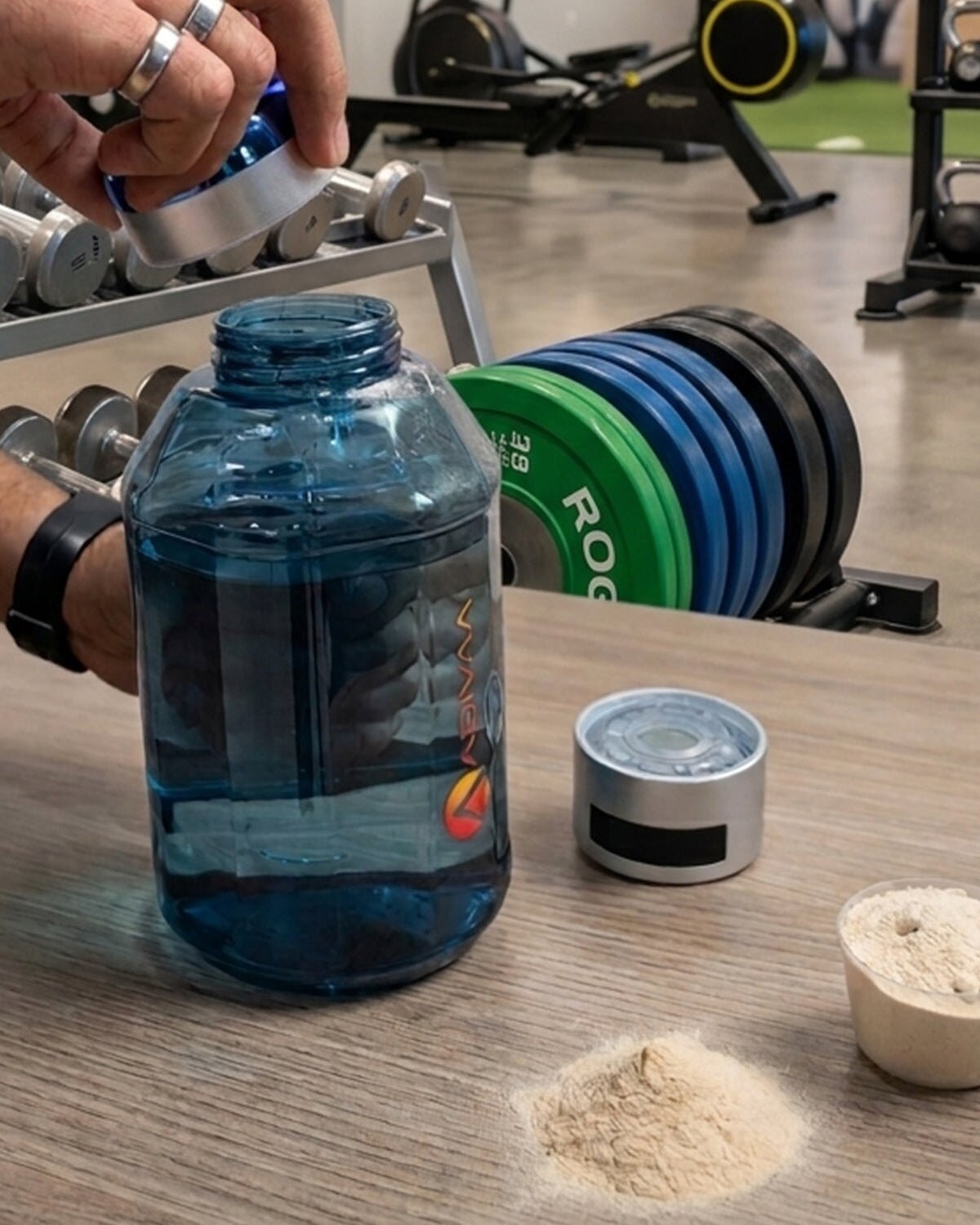 HydroBeast in a gym beside weight plates and a scoop of protein powder