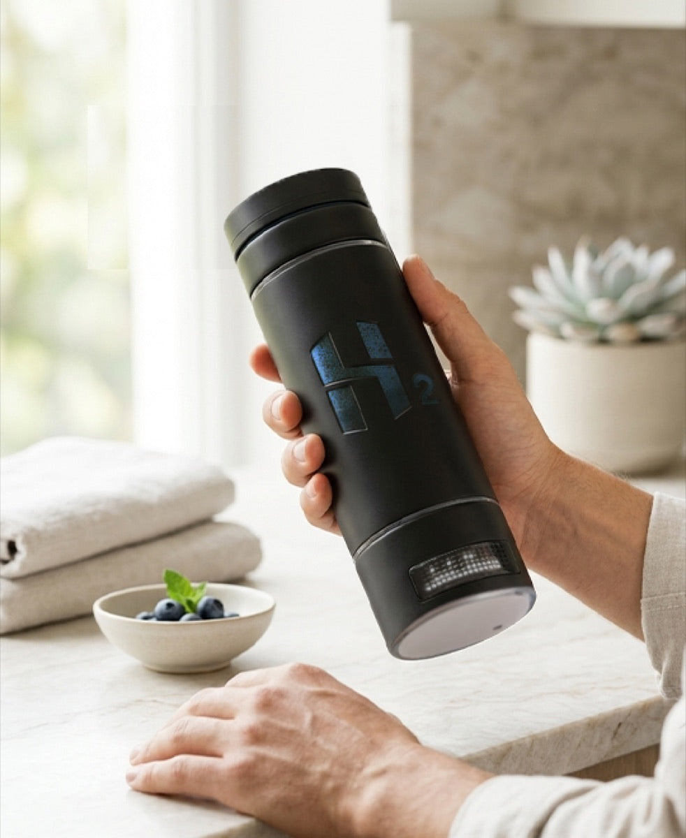 The HydroMax bottle held at a kitchen counter beside a bowl of blueberries