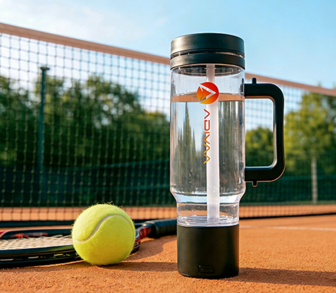 The black HydroSipr on a clay tennis court beside a racket and ball
